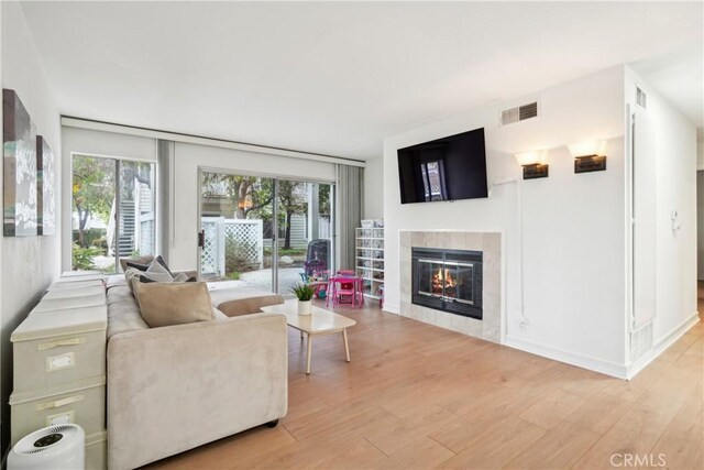 22230 S Vermont Ave Unit 102B, Torrance, CA 90502 - living area with light wood-style floors, a tiled fireplace, and healthy amount of natural light