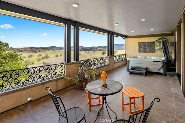 sunroom with a jacuzzi, recessed lighting, tile patterned flooring, and a mountain view