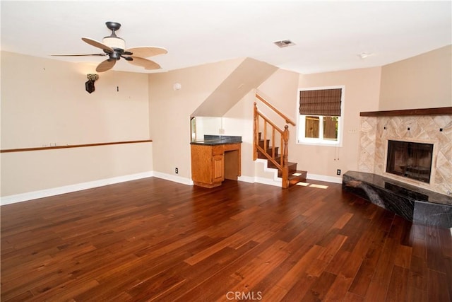 unfurnished living room with ceiling fan, stairs, baseboards, dark wood-type flooring, and visible vents