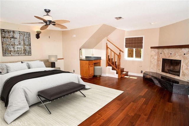 bedroom featuring ceiling fan, visible vents, a fireplace, dark wood finished floors, and baseboards