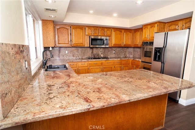 kitchen featuring visible vents, a sink, brown cabinets, and stainless steel appliances