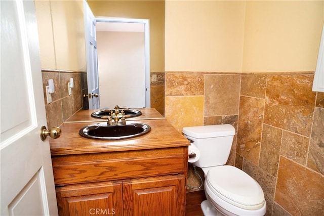 half bathroom with vanity, toilet, and tile walls