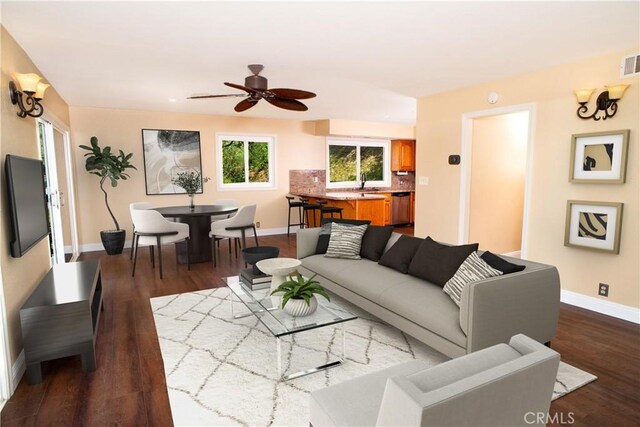 living room featuring baseboards, a ceiling fan, dark wood-style floors, and visible vents