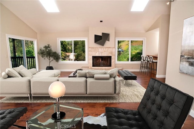 living area with wood finished floors, baseboards, lofted ceiling, and a fireplace