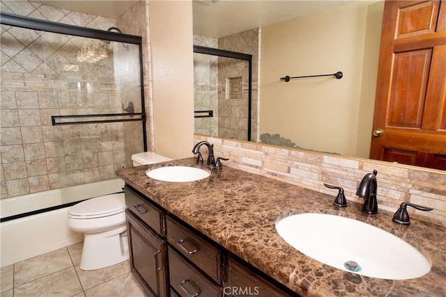 bathroom featuring a sink, decorative backsplash, bath / shower combo with glass door, and toilet