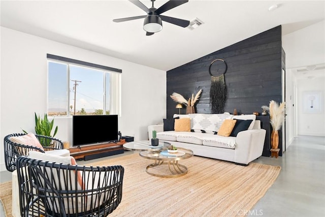 7073 Mission Ave Unit 29, Palms, CA 92277 - living room featuring lofted ceiling, ceiling fan, wooden walls, and finished concrete flooring
