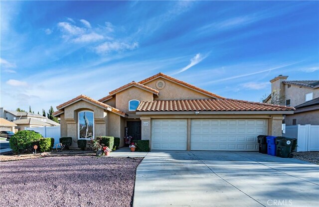 12325 Atoka Ln, Victorville, CA 92392 - mediterranean / spanish house featuring concrete driveway, an attached garage, fence, stucco siding, and a tiled roof