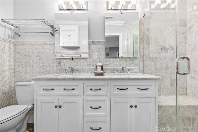 bathroom featuring double vanity, a sink, toilet, and a shower stall