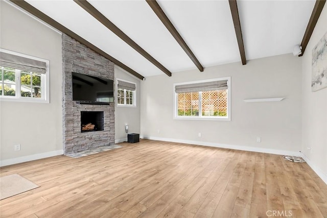 unfurnished living room featuring vaulted ceiling with beams, light wood-style floors, a fireplace, and baseboards