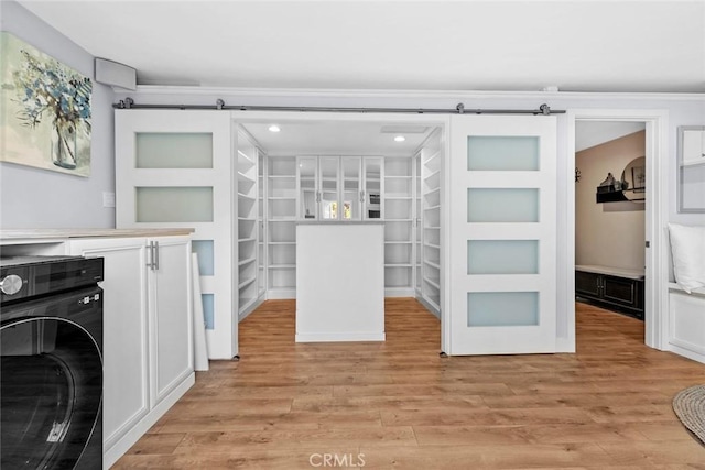 laundry room featuring a barn door, washer / dryer, light wood-style floors, and laundry area