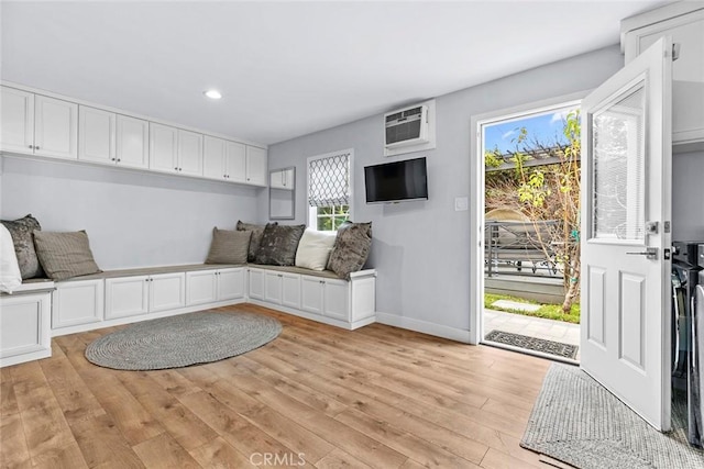 interior space featuring baseboards, light wood-type flooring, a wall mounted AC, and recessed lighting