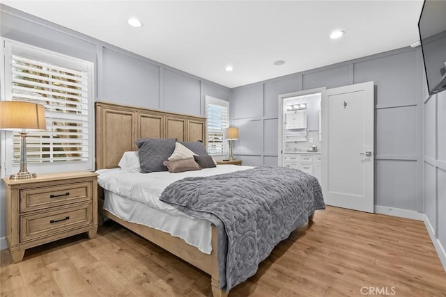 bedroom with a decorative wall, light wood-style floors, and recessed lighting