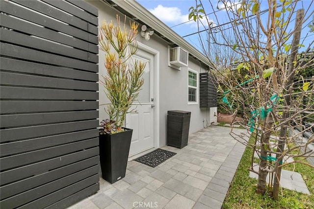 property entrance featuring a wall unit AC, a patio area, and stucco siding