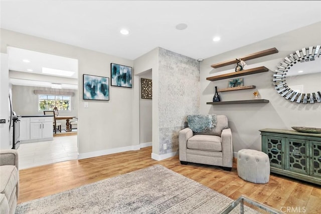 sitting room featuring baseboards, light wood-style flooring, and recessed lighting