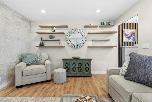 living area with recessed lighting, baseboards, an accent wall, and wood finished floors