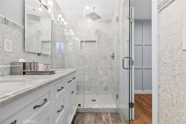 bathroom with double vanity, a sink, tile walls, and a shower stall