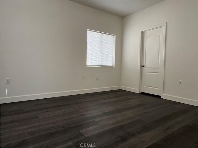 spare room featuring dark wood-type flooring and baseboards