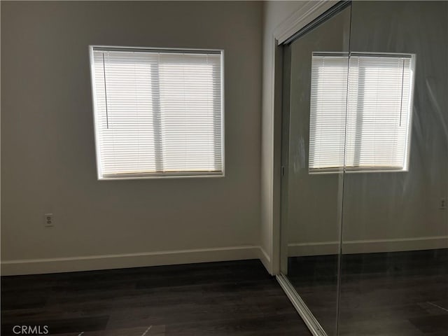 interior space featuring a closet, baseboards, and dark wood finished floors