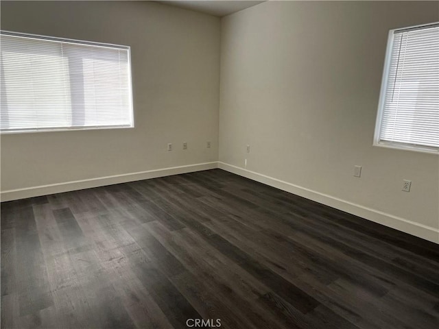 unfurnished room featuring dark wood-type flooring and baseboards
