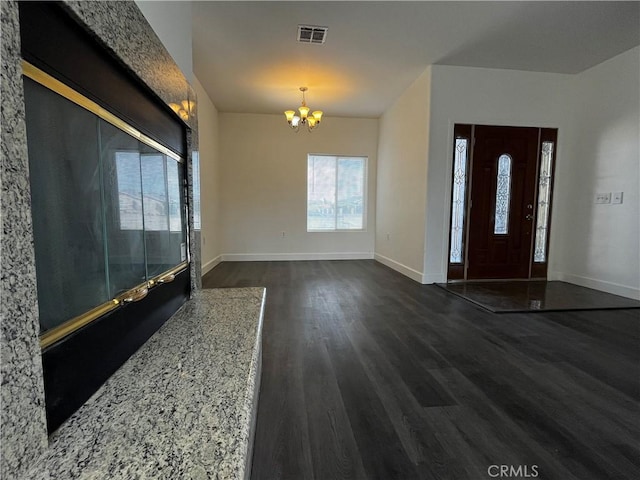 entryway with baseboards, visible vents, a notable chandelier, and dark wood-type flooring