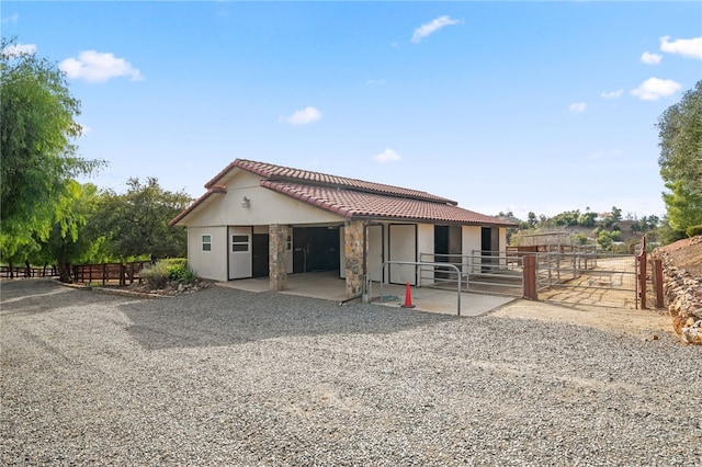 view of front of property with an outdoor structure, a tiled roof, an exterior structure, and stucco siding