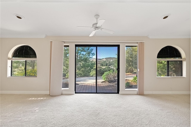 interior space with crown molding, carpet flooring, baseboards, and a ceiling fan