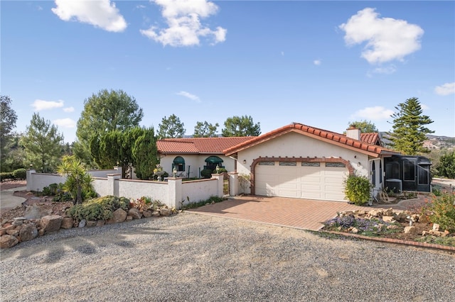 mediterranean / spanish home with decorative driveway, stucco siding, an attached garage, a fenced front yard, and a tile roof
