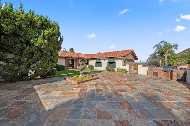mediterranean / spanish-style home featuring stucco siding, exterior kitchen, and a tile roof