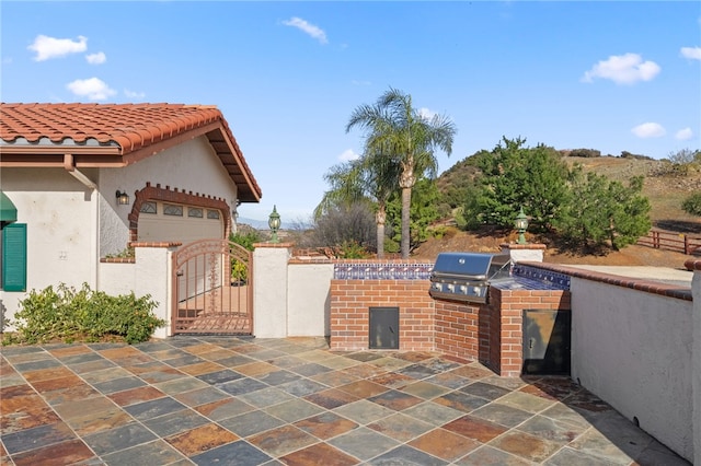 view of patio with fence, a gate, an attached garage, and area for grilling