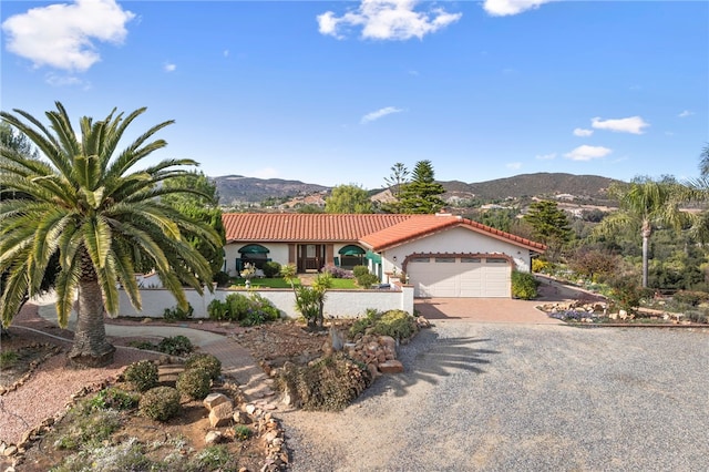 view of front of home with a garage, a mountain view, a tiled roof, and driveway