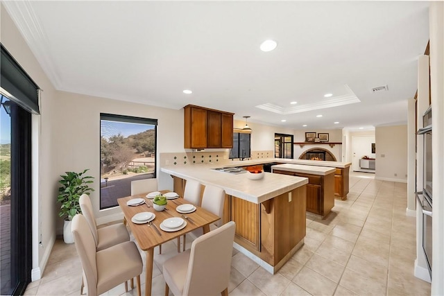 kitchen with brown cabinets, light countertops, a peninsula, recessed lighting, and visible vents