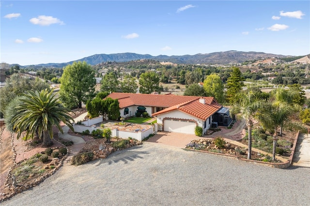 view of front facade with a garage, a mountain view, a tiled roof, and driveway