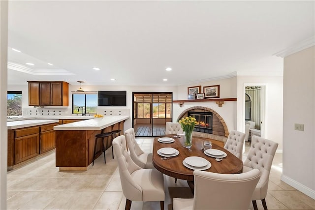 dining room with ornamental molding, a glass covered fireplace, baseboards, recessed lighting, and light tile patterned floors