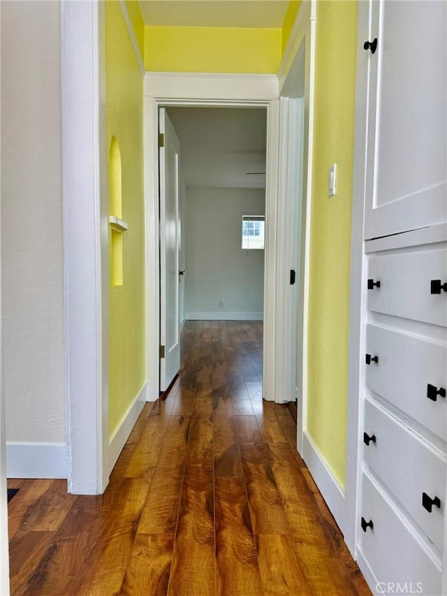 hall featuring dark wood-type flooring and baseboards