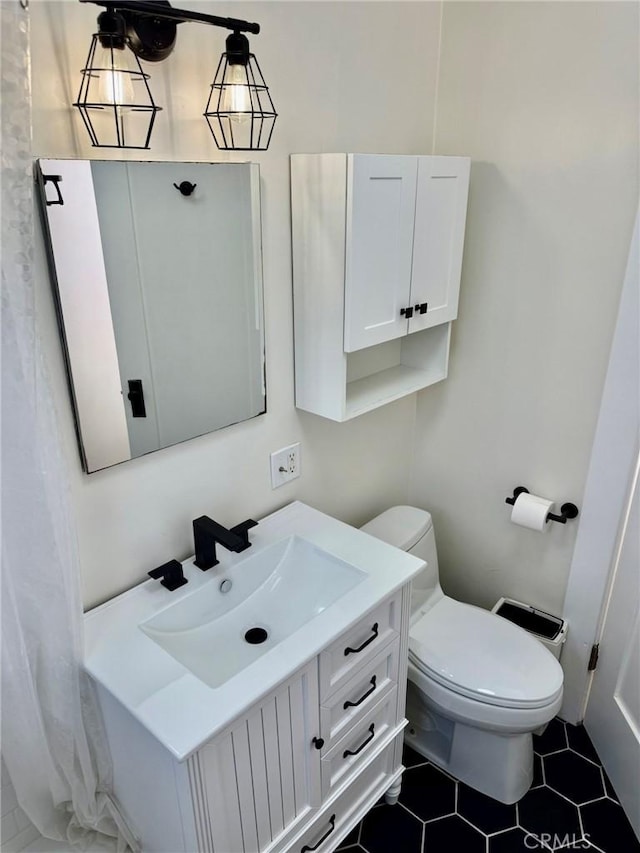 bathroom with toilet, vanity, and tile patterned floors