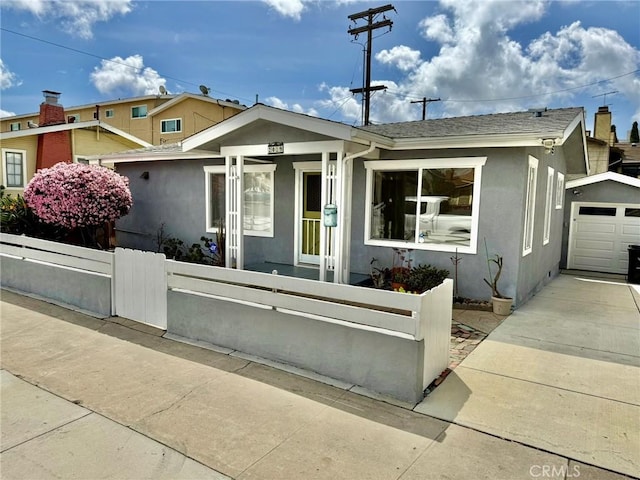 view of front facade with a gate, a fenced front yard, stucco siding, concrete driveway, and a garage