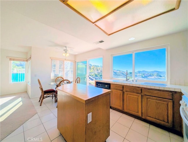 kitchen with a kitchen island, a sink, visible vents, dishwasher, and brown cabinets