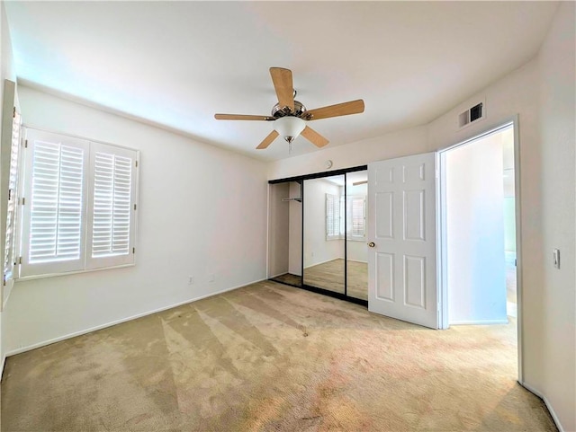 unfurnished bedroom with a closet, carpet floors, ceiling fan, and visible vents