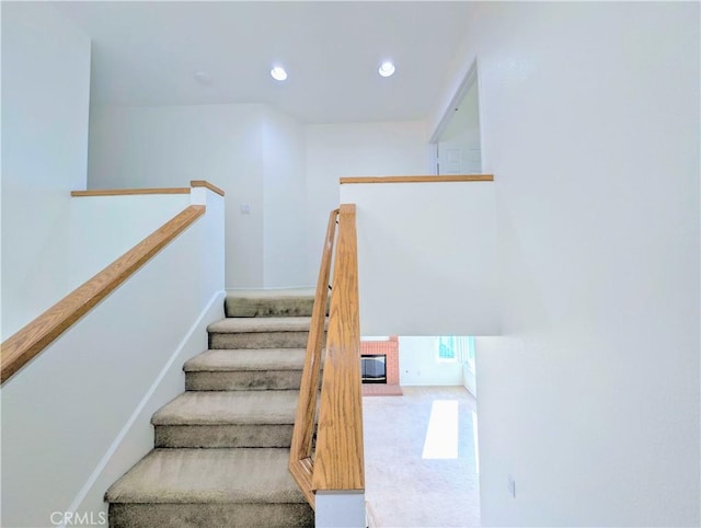 stairs featuring a brick fireplace and recessed lighting