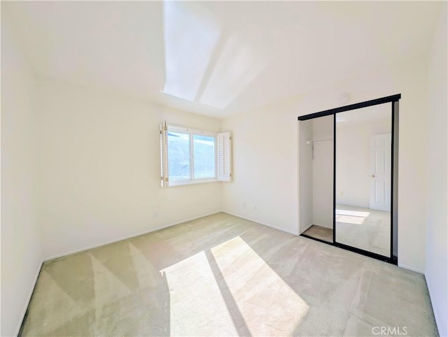 unfurnished bedroom featuring light carpet and a closet
