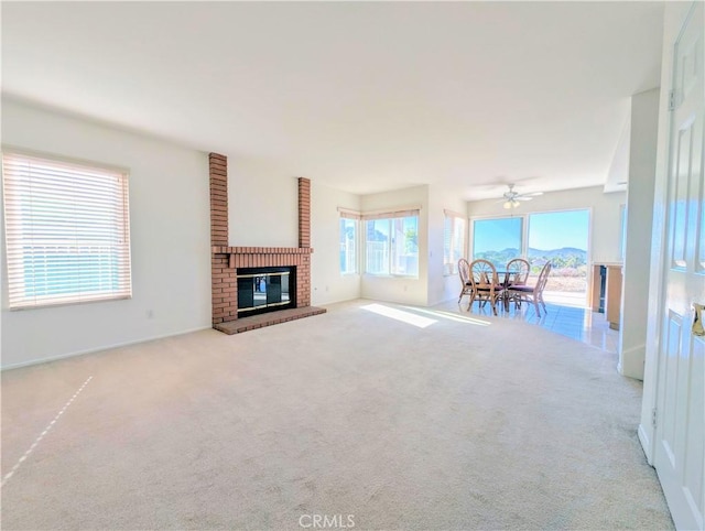 unfurnished living room featuring a fireplace, carpet floors, and ceiling fan