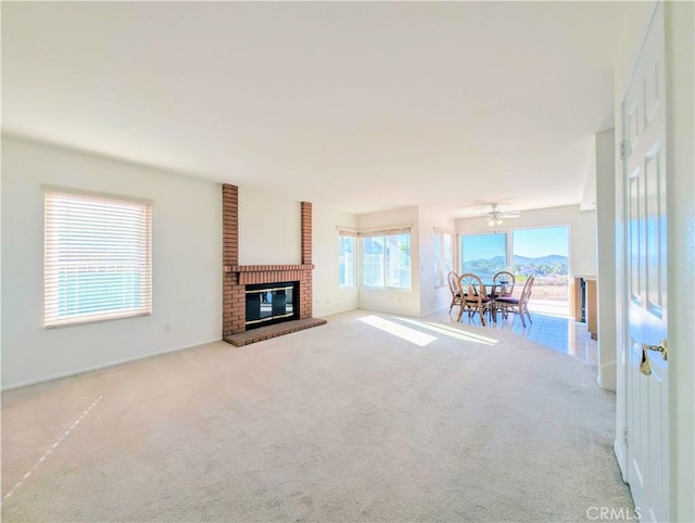unfurnished living room featuring a fireplace, ceiling fan, and carpet