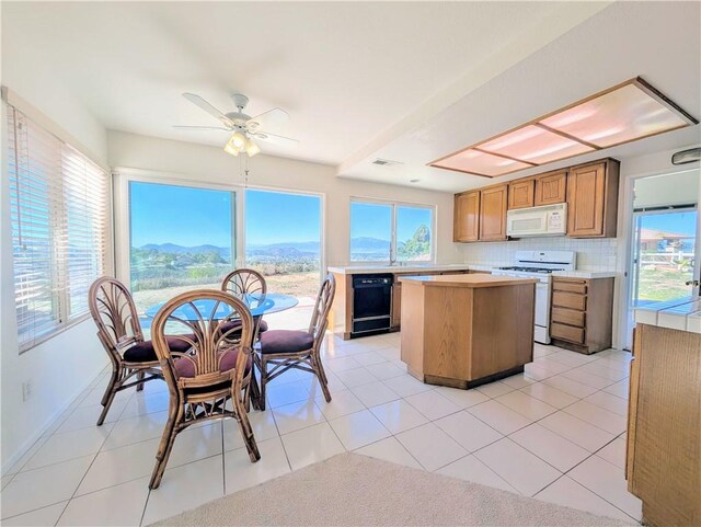 kitchen featuring a center island, white appliances, light countertops, and a healthy amount of sunlight