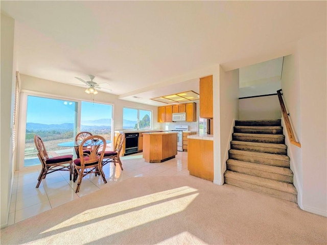 dining room featuring light tile patterned floors, light carpet, stairs, and ceiling fan