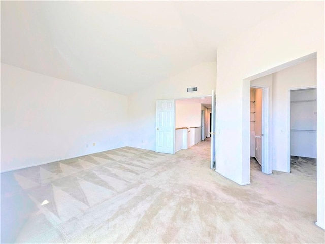 empty room with light colored carpet, vaulted ceiling, and visible vents
