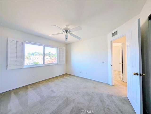 unfurnished room featuring light carpet, visible vents, and a ceiling fan