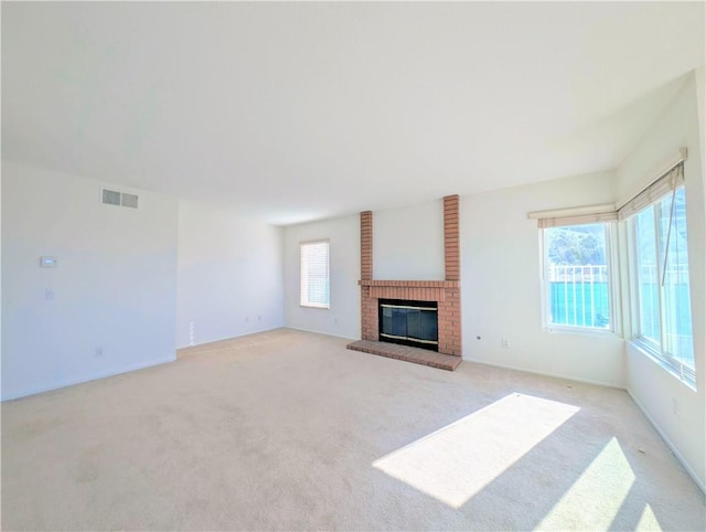 unfurnished living room featuring light carpet, visible vents, and a fireplace