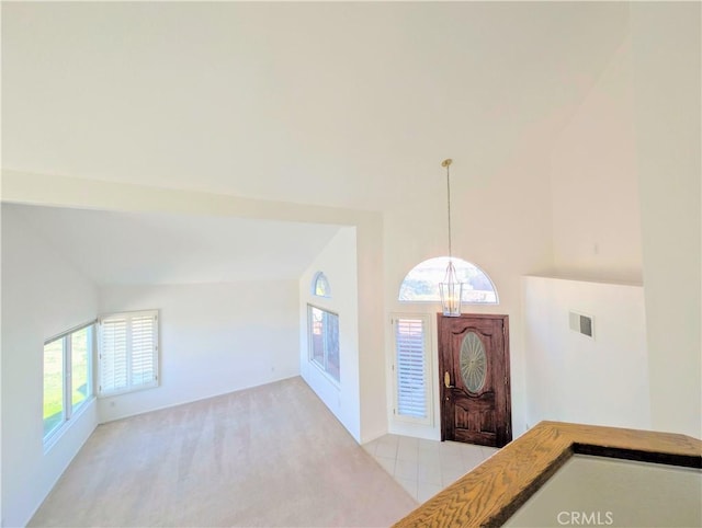 entrance foyer with light carpet, visible vents, high vaulted ceiling, and an inviting chandelier