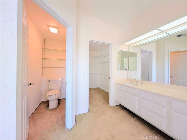 bathroom with visible vents, a spacious closet, toilet, and vanity
