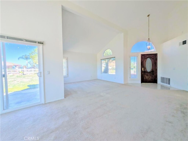 carpeted foyer with high vaulted ceiling and visible vents